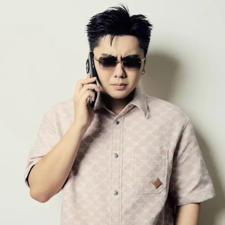 Press shot of rapper Skai ISYOURGOD holding a phone up to his right ear in front of a white background